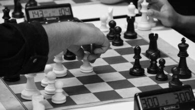 Close-up of a strategic chess match in progress, highlighting focused hands and chess pieces.