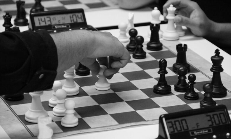 Close-up of a strategic chess match in progress, highlighting focused hands and chess pieces.