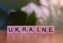 Wooden Scrabble tiles spelling 'UKRAINE' on a table with blurred background.