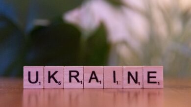 Wooden Scrabble tiles spelling 'UKRAINE' on a table with blurred background.