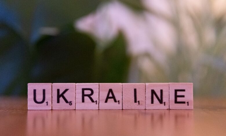 Wooden Scrabble tiles spelling 'UKRAINE' on a table with blurred background.