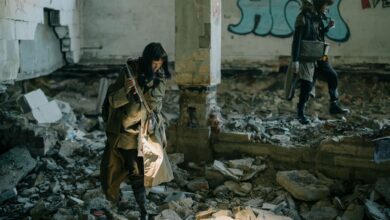 Two people exploring a desolate, abandoned building, embodying a post-apocalyptic theme.
