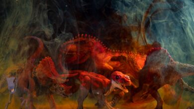 Vibrant dinosaur toy figures enveloped in colored smoke create a dramatic still life composition.