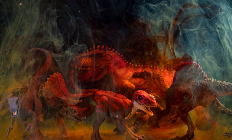 Vibrant dinosaur toy figures enveloped in colored smoke create a dramatic still life composition.