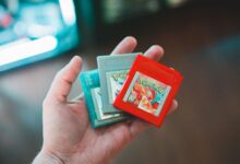 Hand holding vintage Pokemon game cartridges, showcasing nostalgic gaming.