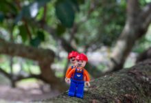 Colorful LEGO figure on tree branch, blending creativity with nature.