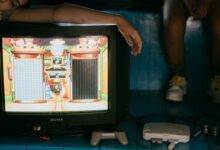 Crop unrecognizable female on modern monitor with video game on screen near ethnic partner