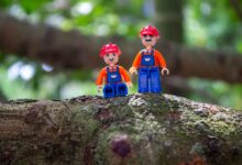 Colorful toy figures with helmets on a tree branch, showcasing creativity and playfulness.