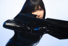 A person in sleek black cosplay attire holds a futuristic weapon, exuding a sci-fi vibe.