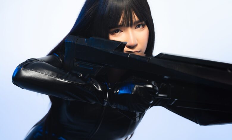 A person in sleek black cosplay attire holds a futuristic weapon, exuding a sci-fi vibe.