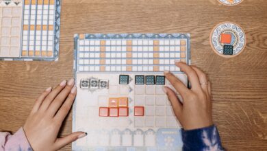 Hands arranging tiles on a strategic board game during a fun game night.