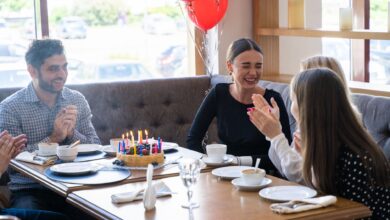 Friends celebrate a birthday with cake and laughter at a cozy restaurant setting.