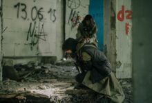 Two individuals exploring a decaying building with graffiti, embodying a post-apocalyptic theme.