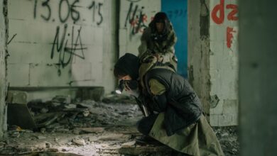 Two individuals exploring a decaying building with graffiti, embodying a post-apocalyptic theme.