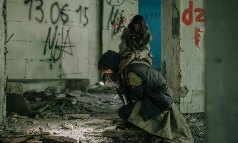 Two individuals exploring a decaying building with graffiti, embodying a post-apocalyptic theme.