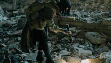 Person exploring an abandoned urban ruin with a flashlight, amidst debris and decay.