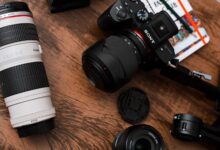 Close-up of various camera lenses and equipment on a wooden table.
