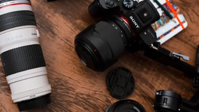 Close-up of various camera lenses and equipment on a wooden table.
