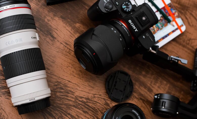 Close-up of various camera lenses and equipment on a wooden table.