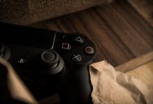 A close-up of a PlayStation gaming controller resting on a wooden surface with a rustic feel.