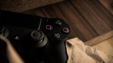 A close-up of a PlayStation gaming controller resting on a wooden surface with a rustic feel.