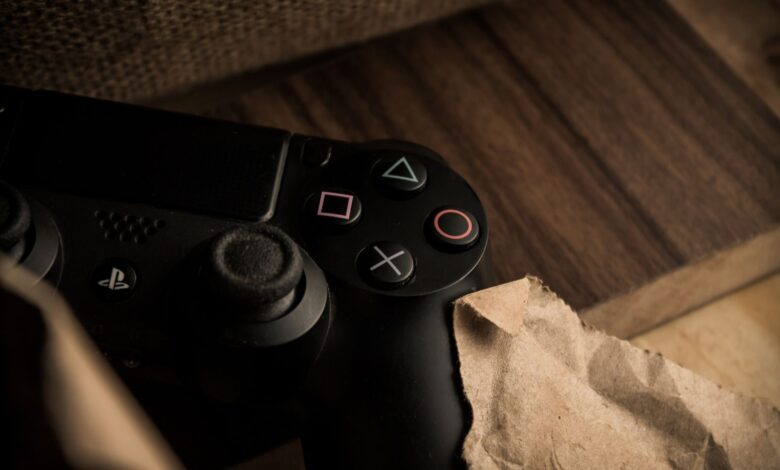 A close-up of a PlayStation gaming controller resting on a wooden surface with a rustic feel.