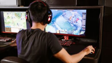 Adult male gamer immersed in PC gaming on dual monitors with headphones indoors.