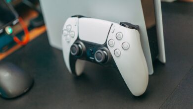 Close-up of a PlayStation 5 controller resting on its console, showcasing modern gaming technology.