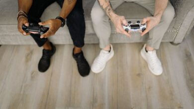 Two friends with gaming controllers focusing on a video game indoors from above.