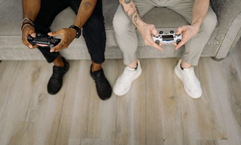 Two friends with gaming controllers focusing on a video game indoors from above.