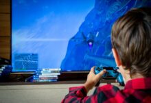 Young boy playing video game on TV with PS4 controller, enjoying leisure time indoors.
