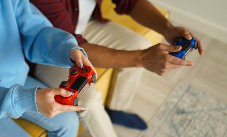 Two adults holding wireless game controllers while playing video games indoors.