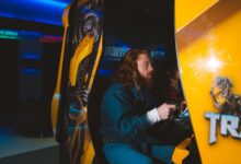 Bearded man passionately gaming at an arcade, focused and engaged.