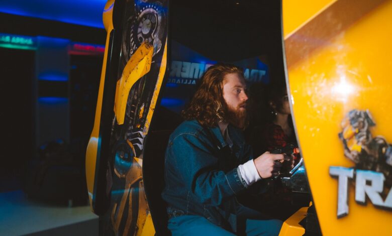 Bearded man passionately gaming at an arcade, focused and engaged.