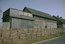 Traditional wooden house alongside a woven fence in Pāvilosta, Latvia.