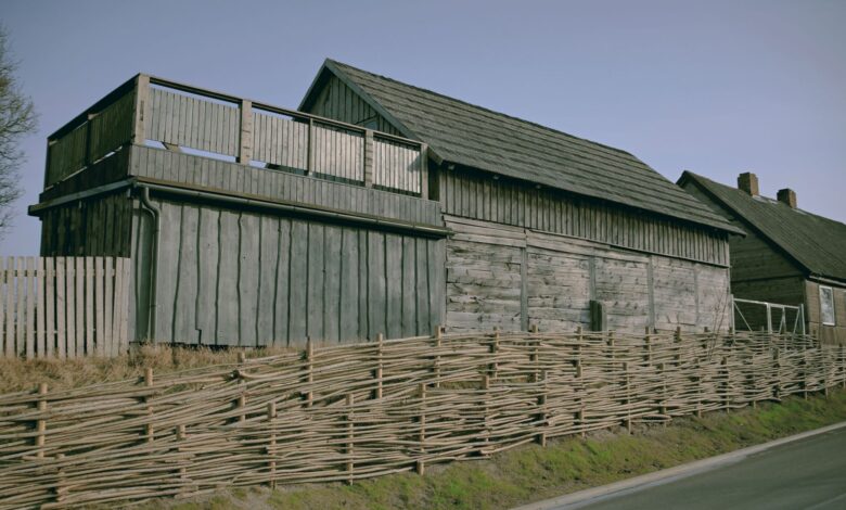 Traditional wooden house alongside a woven fence in Pāvilosta, Latvia.