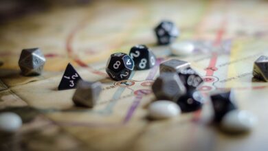 Focus on black and white polyhedral dice scattered on a board game map, suggesting strategy and chance.