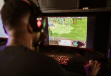 A gamer intensely playing a strategy game on a high-resolution monitor indoors.