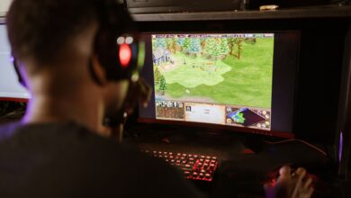 A gamer intensely playing a strategy game on a high-resolution monitor indoors.