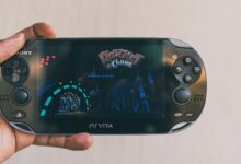Close-up of a hand holding a PlayStation Vita with Ratchet & Clank displayed on screen. Captured in Johannesburg.