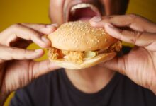 A man enjoying a tasty chicken burger, highlighting fast food cravings and deliciousness.