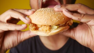 A man enjoying a tasty chicken burger, highlighting fast food cravings and deliciousness.