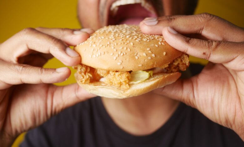 A man enjoying a tasty chicken burger, highlighting fast food cravings and deliciousness.