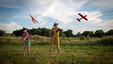 Two kids enjoying a sunny day outdoors, playing with toy airplanes.