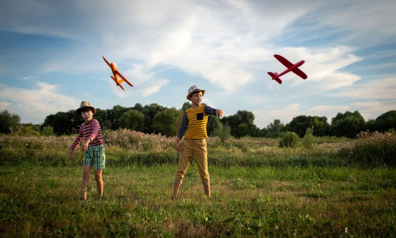 Two kids enjoying a sunny day outdoors, playing with toy airplanes.