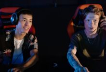 Two young men focused on an intense gaming session in a dark room, participating in a team esports tournament.