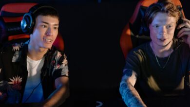 Two young men focused on an intense gaming session in a dark room, participating in a team esports tournament.