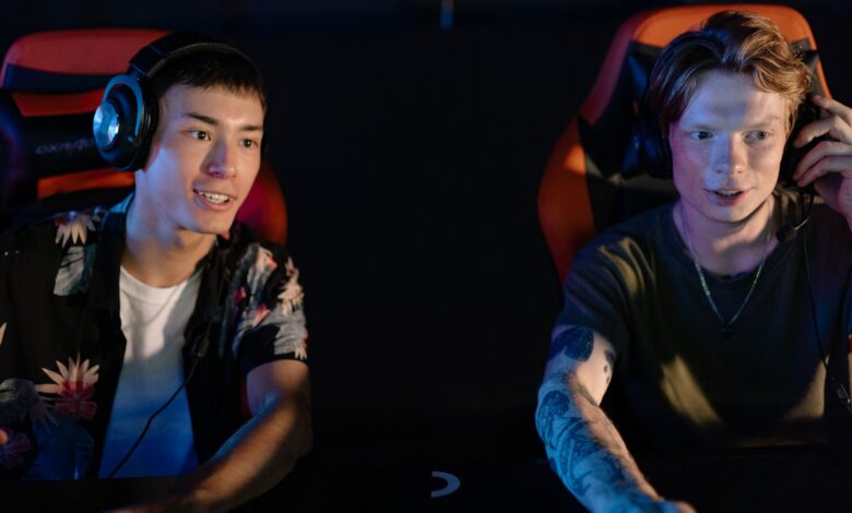 Two young men focused on an intense gaming session in a dark room, participating in a team esports tournament.