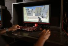Person engaging in a shooting video game on a high-performance setup with mechanical keyboard.