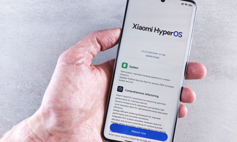 Close-up of a hand holding a Xiaomi smartphone with HyperOS interface, showcasing comprehensive refactoring and system update details.